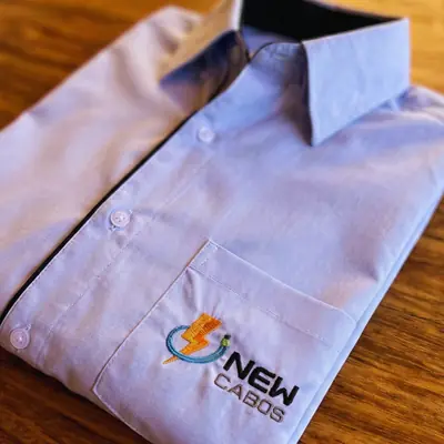Camisa social azul clara com o logo da New Cabos bordado no bolso