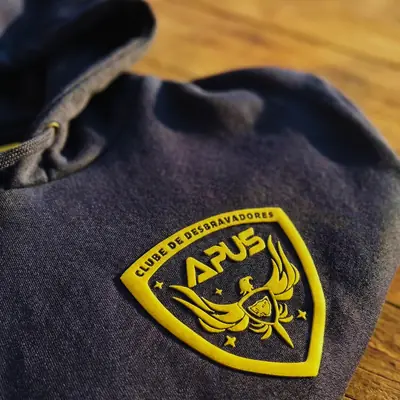 Moletom cinza com o brasão do Clube de Desbravadores Apus aplicado no peito