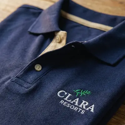 Polo azul-marinho com o logo da Clara Resorts bordado no peito